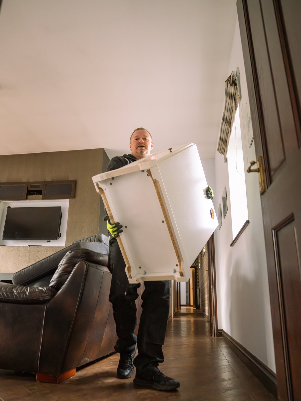 Removal worker carrying furniture during house move