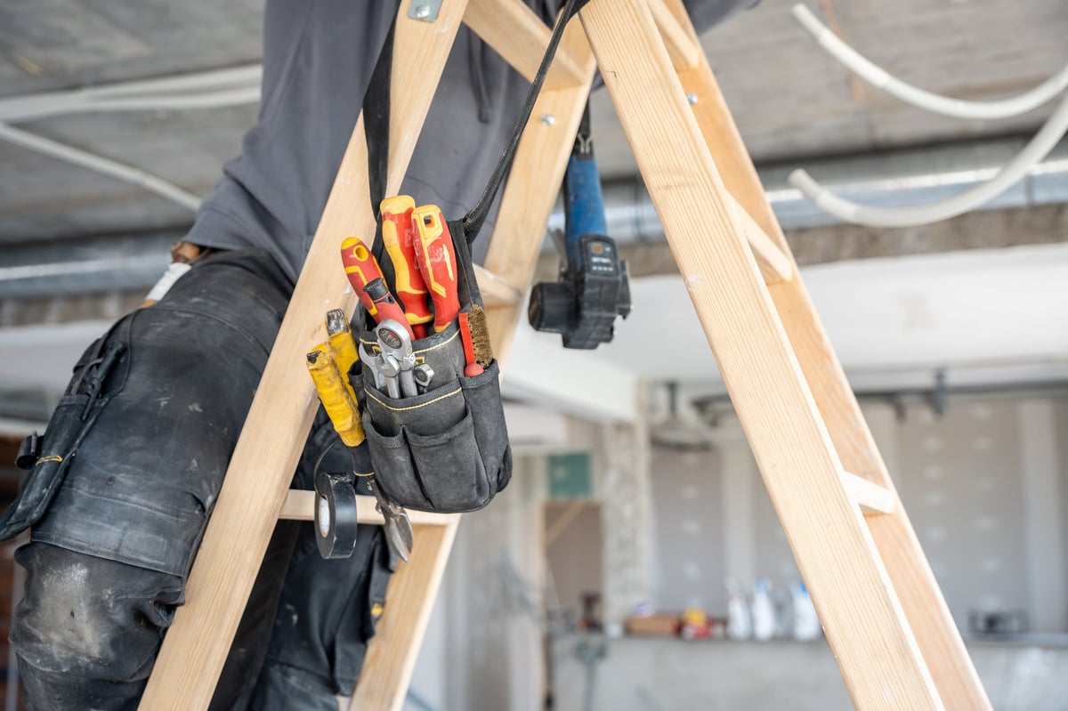 Construction worker with tools on ladder